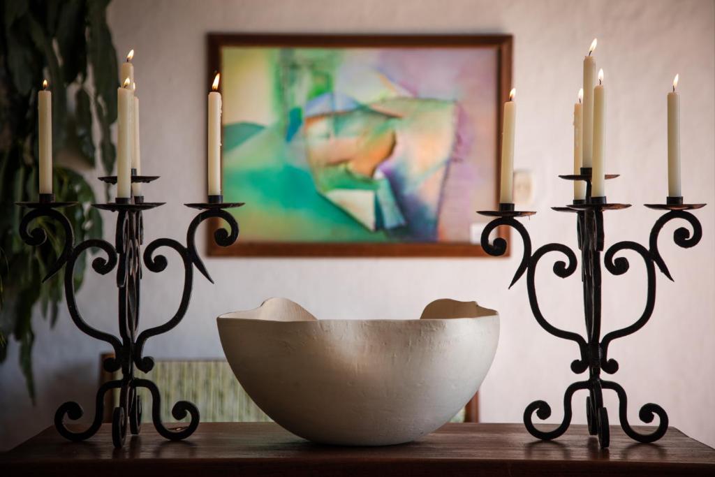 two candles and a bowl on a table with two candlesticks at Posada del Campanario in Barichara