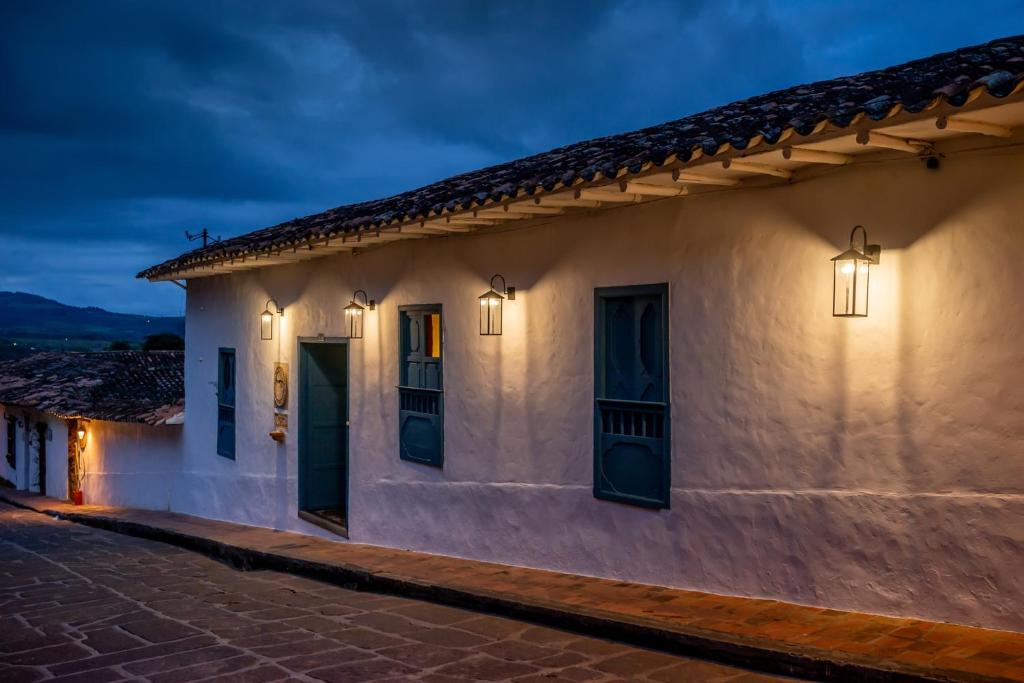 a white building with green doors on a street at Posada del Campanario in Barichara