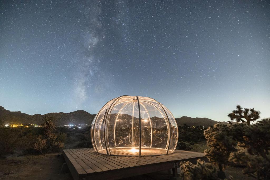 a glass dome sitting on a wooden table at night at New: Dome, Hot Tub, Game Room, 5 min to park in Joshua Tree