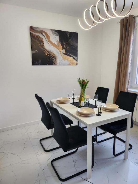 einen weißen Esstisch mit schwarzen Stühlen und einem Kronleuchter in der Unterkunft Apartament z widokiem in Zgorzelec