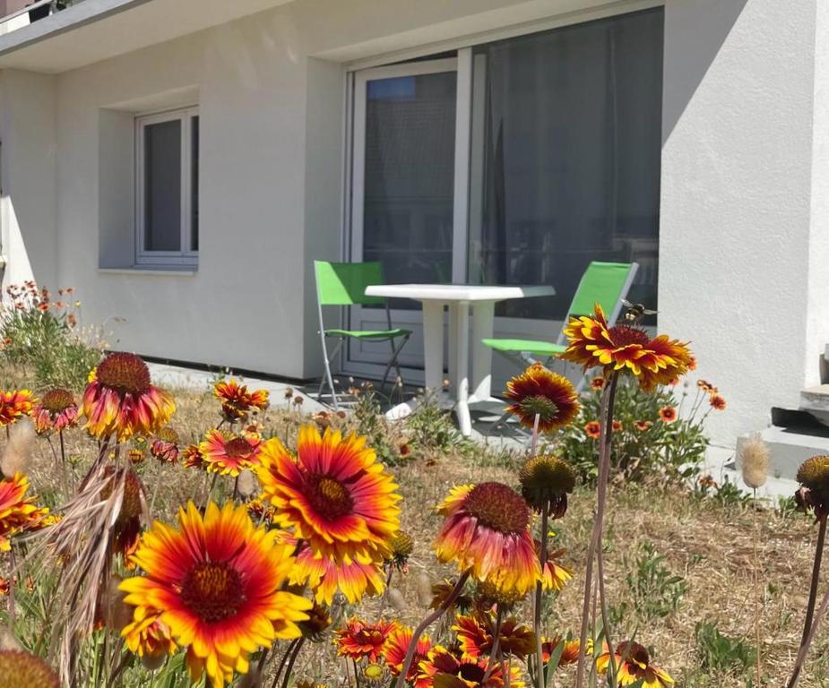 a garden with flowers and a table and chairs at Ste Cécile Plage in Camiers