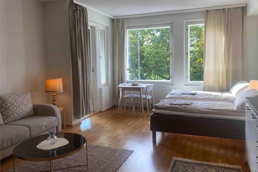 a bedroom with a bed and a couch and a table at Parvekkeellinen moderni asunto in Turku