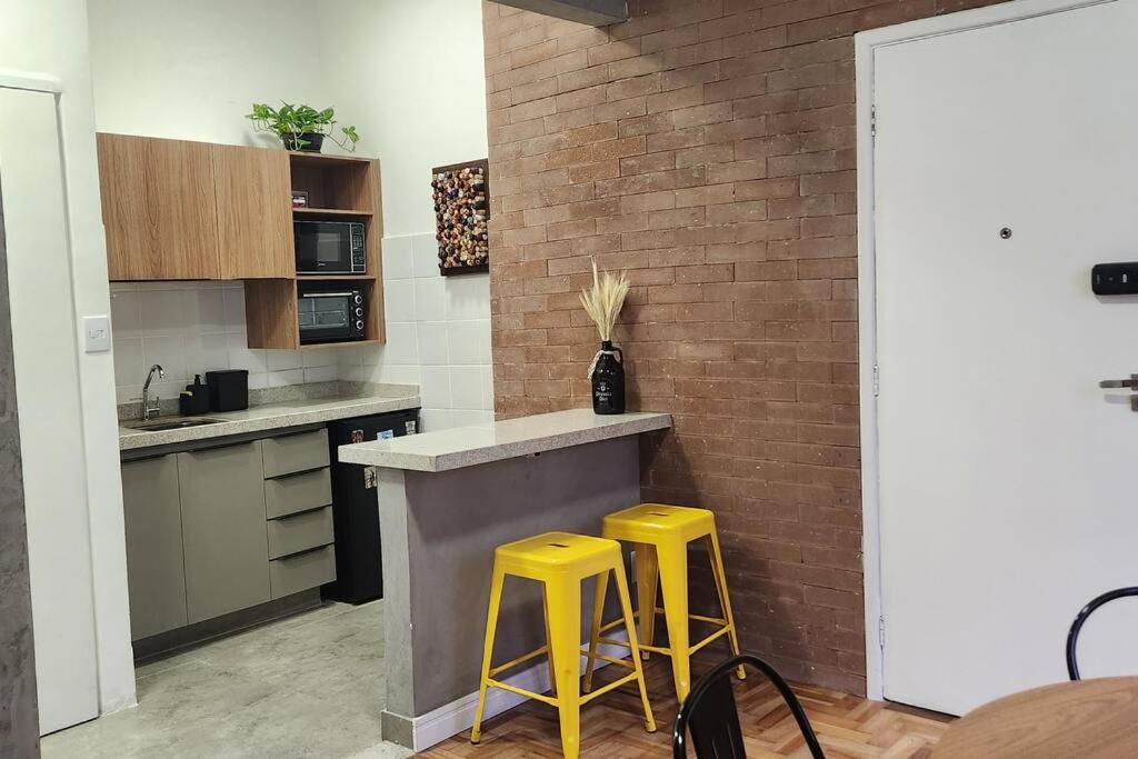 uma cozinha com dois bancos amarelos num balcão em Seu Lugar em Beagá em Belo Horizonte