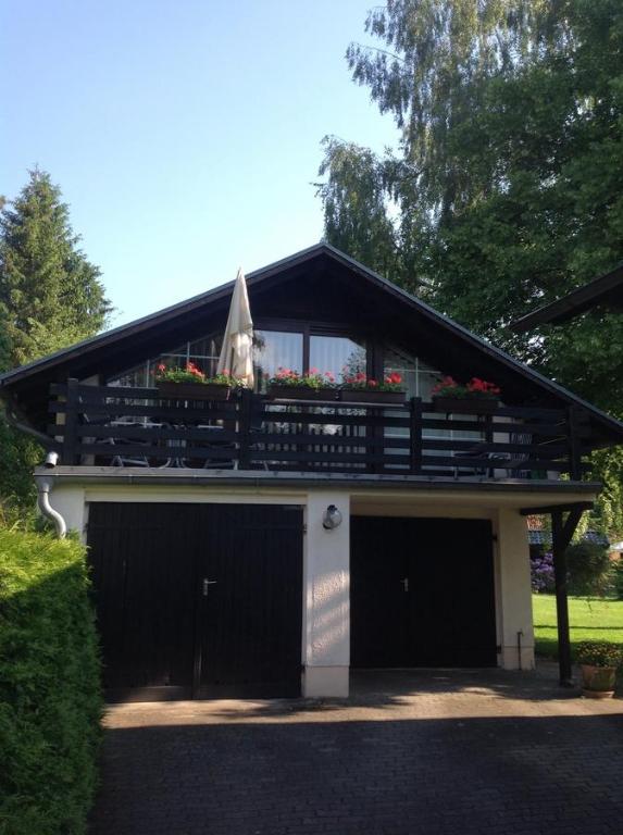 ein Gebäude mit zwei Garagentüren und einem Balkon mit Blumen in der Unterkunft Bad Saarow Ferienhaus Am Hafen in Bad Saarow
