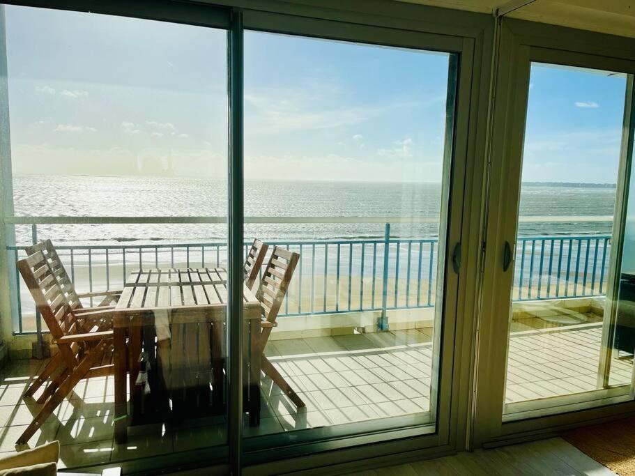 une table et des chaises sur un balcon avec vue sur l'océan dans l'établissement Vue mer Appartement Le Miramar, à La Baule