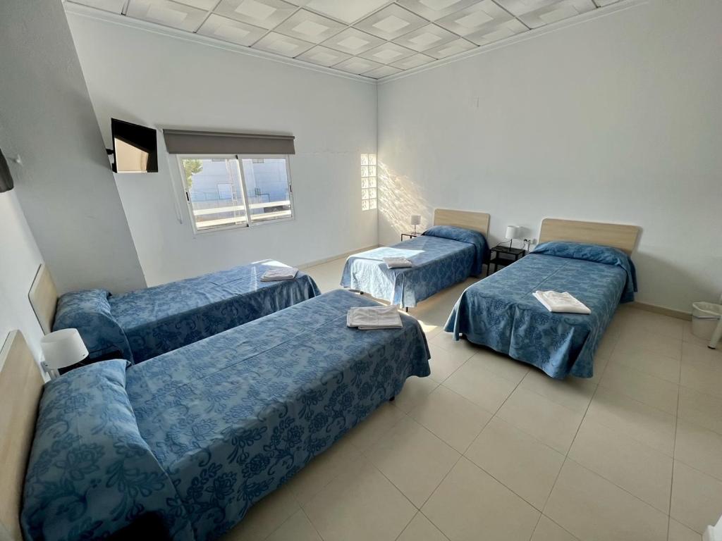 Habitación con 3 camas y sofá. en Hostal Kaizen, en La Nucía