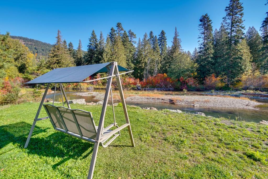 a swing in the grass next to a river at Cozy Easton Cabin on the Yakima River! in Pine Glen