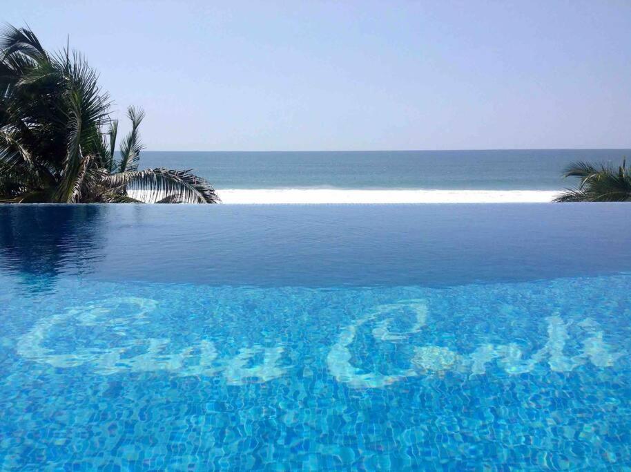 a blue swimming pool with the ocean in the background at Casa Conti Agua Blanca in Playa Agua Blanca