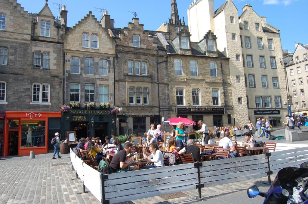 un grupo de personas sentadas en las mesas frente a los edificios en Grassmarket-Old Town Apartment, en Edimburgo