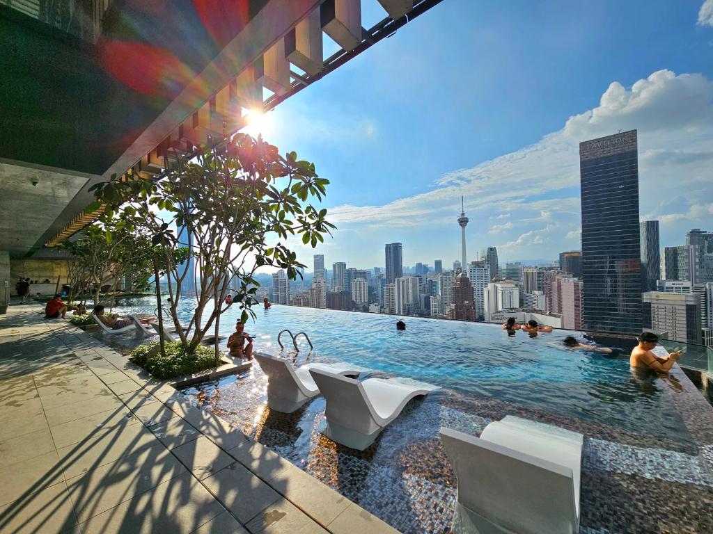 a swimming pool with white chairs and a city skyline at The Axon Residence Bukit Bintang in Kuala Lumpur
