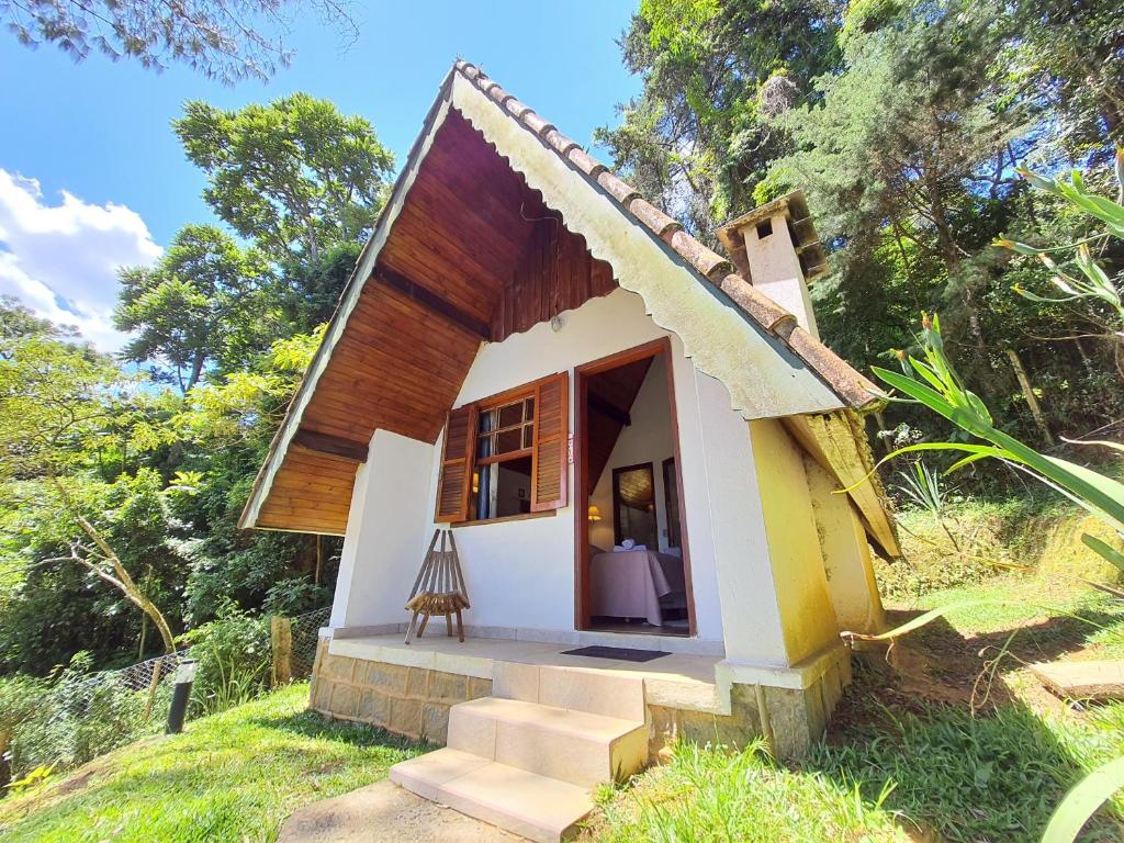 a small house with a porch in a field at Recanto das Hortencias Hotel in Monte Verde