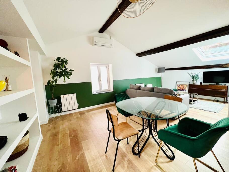 uma sala de estar com uma mesa de vidro e cadeiras verdes em Le Faubourg ! Appartement Type 3 em Nancy