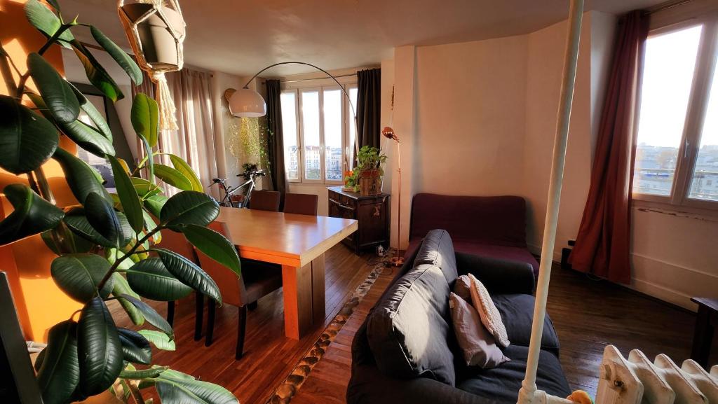 un soggiorno con divano e tavolo con piante di Grand appartement ouvert type loft avec vue dégagée proche La Défense & U Arena a La Garenne-Colombes