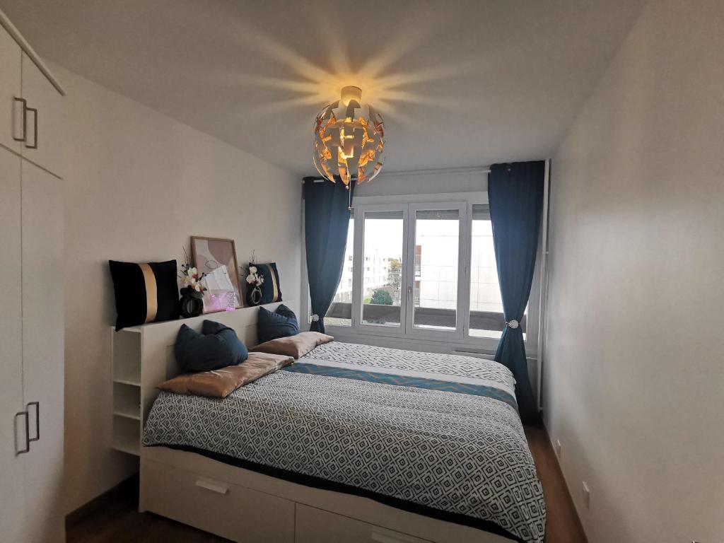 1 dormitorio con cama y lámpara de araña en Chambre Cozy avec Vue Panoramique sur la Seine, Proche de Paris et de l'Aéroport Orly, en Choisy-le-Roi