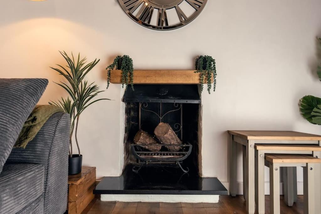 a fireplace in a living room with a clock on the wall at Cosy hillside cottage in Great Malvern
