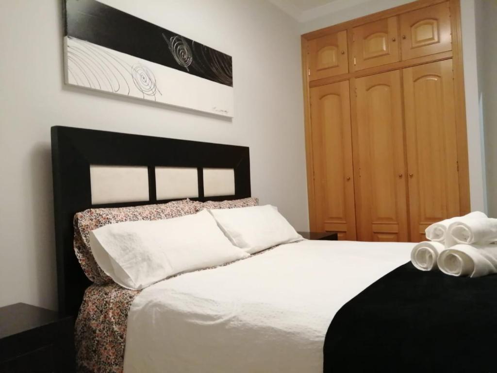 um quarto com uma cama branca e uma porta de madeira em Apartamento La Muralla II em Baena