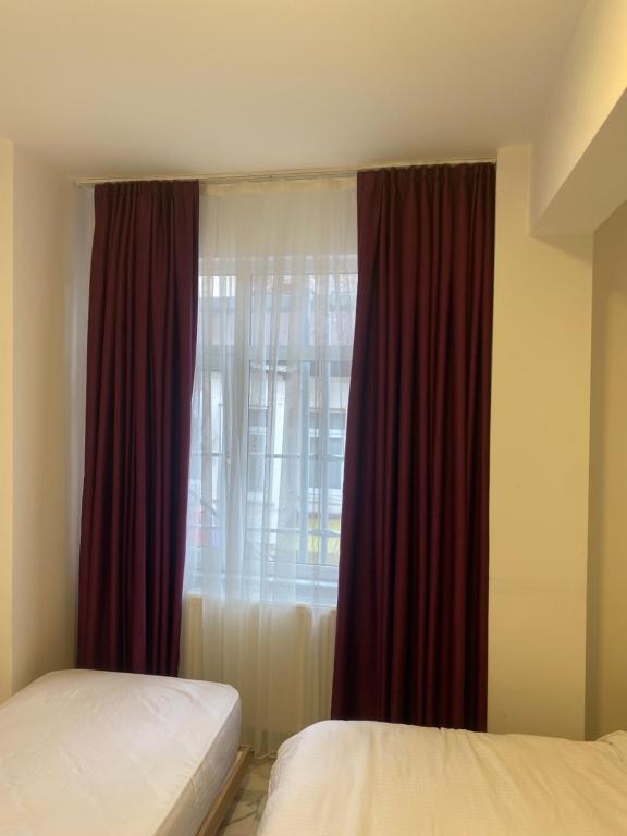 a bedroom with two beds and a window with red curtains at yenikapı hotel in Istanbul