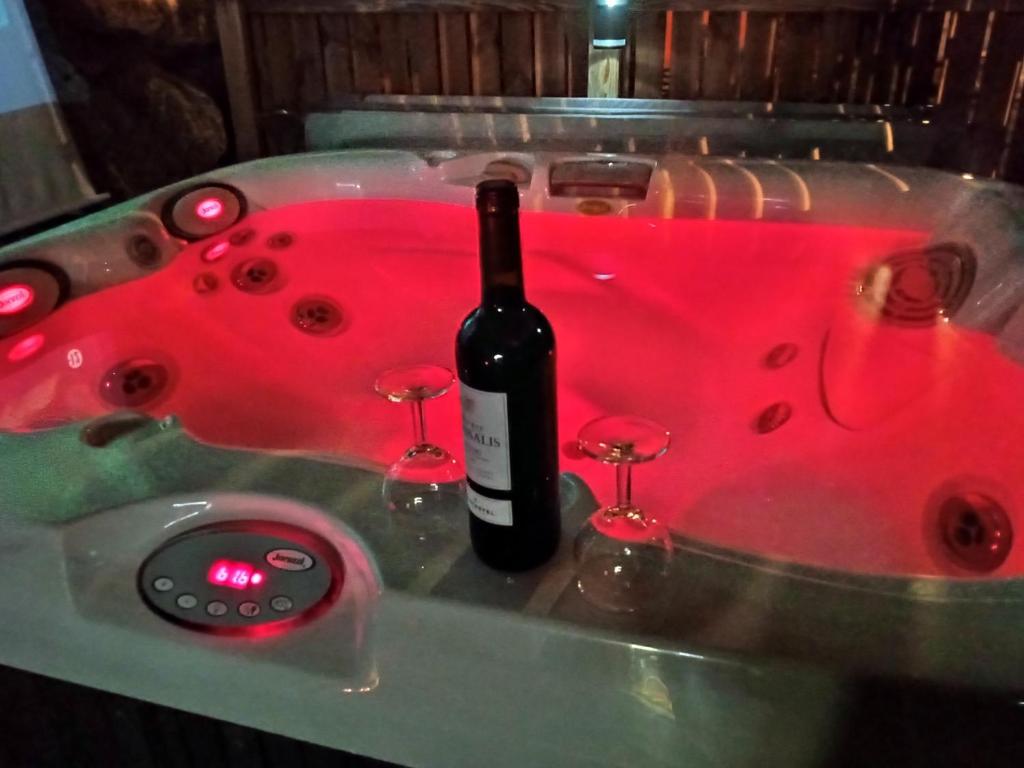 Una botella de vino en una bañera roja con copas de vino en LE LOVE CHALET DES ALPES, en Guillestre