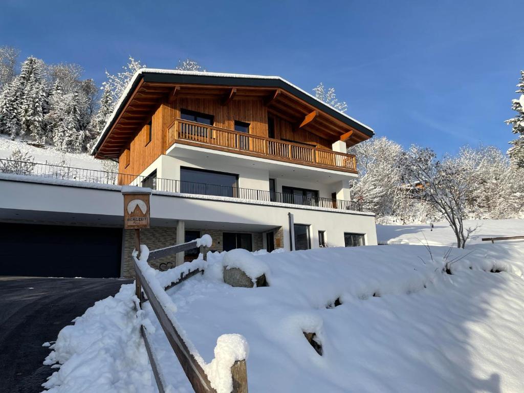 un edificio con nieve delante en Bergzeit Appartement, en Hopfgarten im Brixental