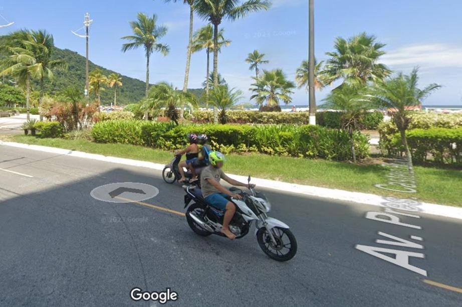 zwei Personen, die auf einem Motorrad eine Straße hinunter fahren in der Unterkunft Kit Canto do Forte - Praia Grande in Praia Grande