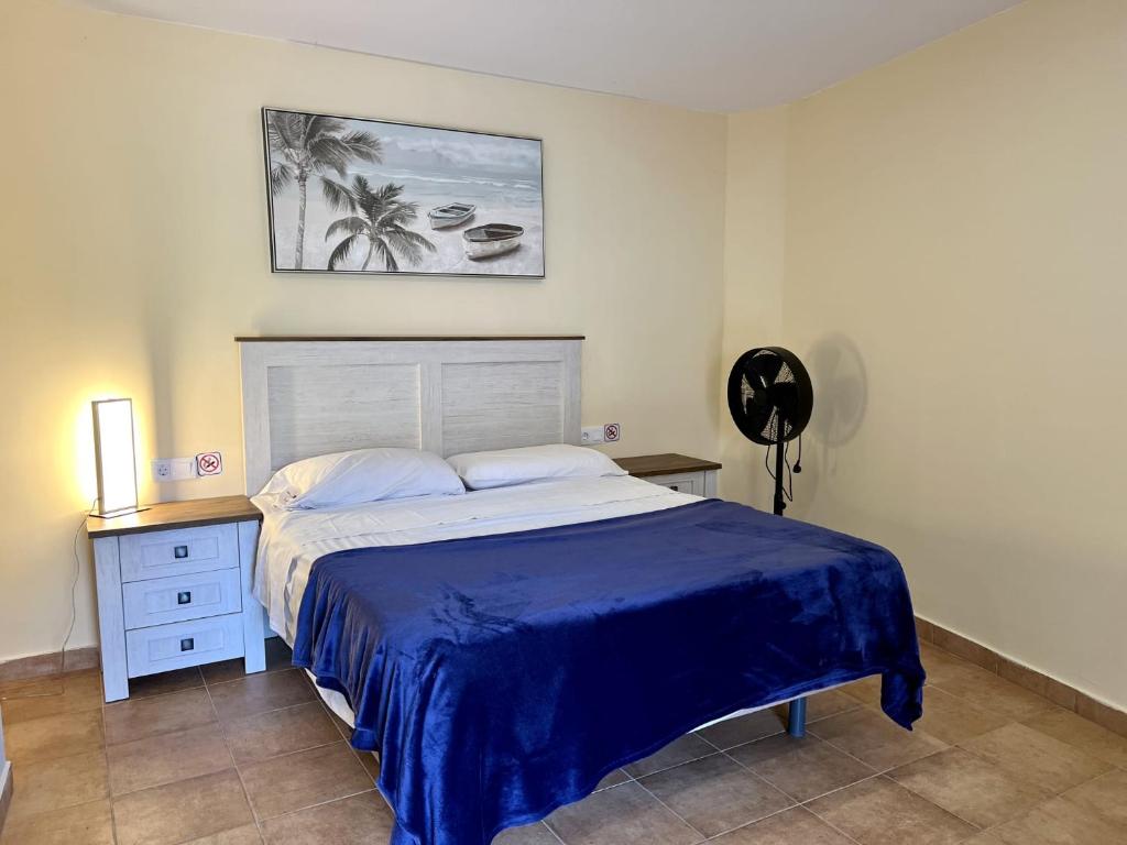 a bedroom with a bed with a blue bedspread at Winter Wonderland in Puerto de Santiago