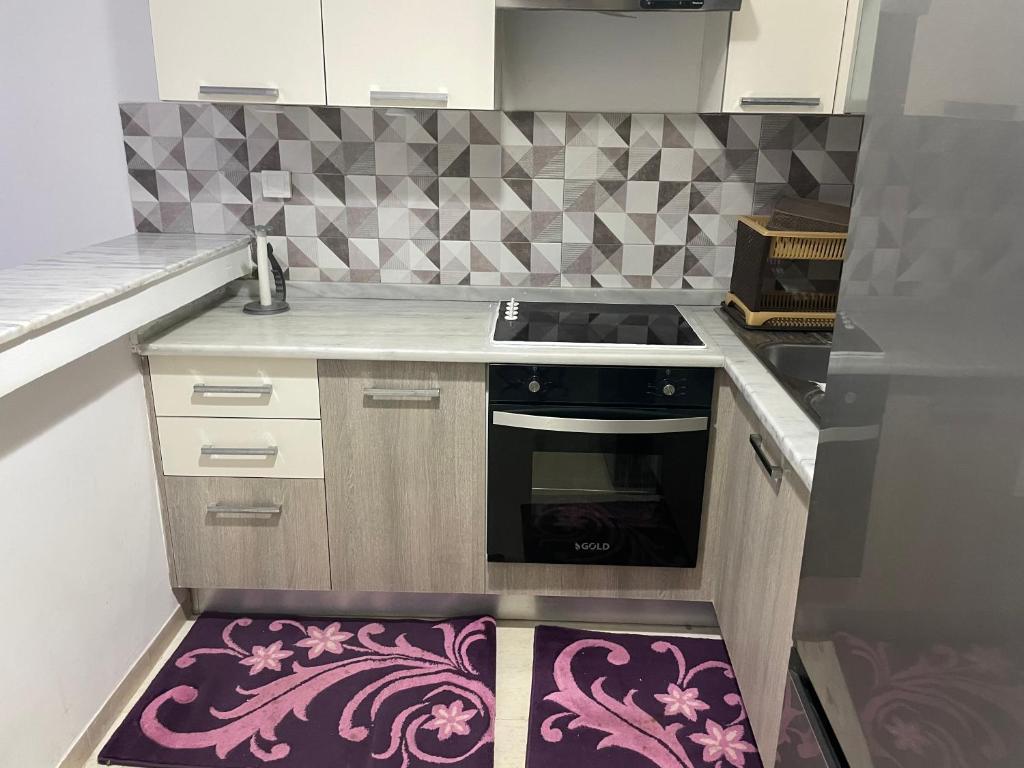une cuisine avec cuisinière et tapis violet dans l'établissement Molk, à Manūbah