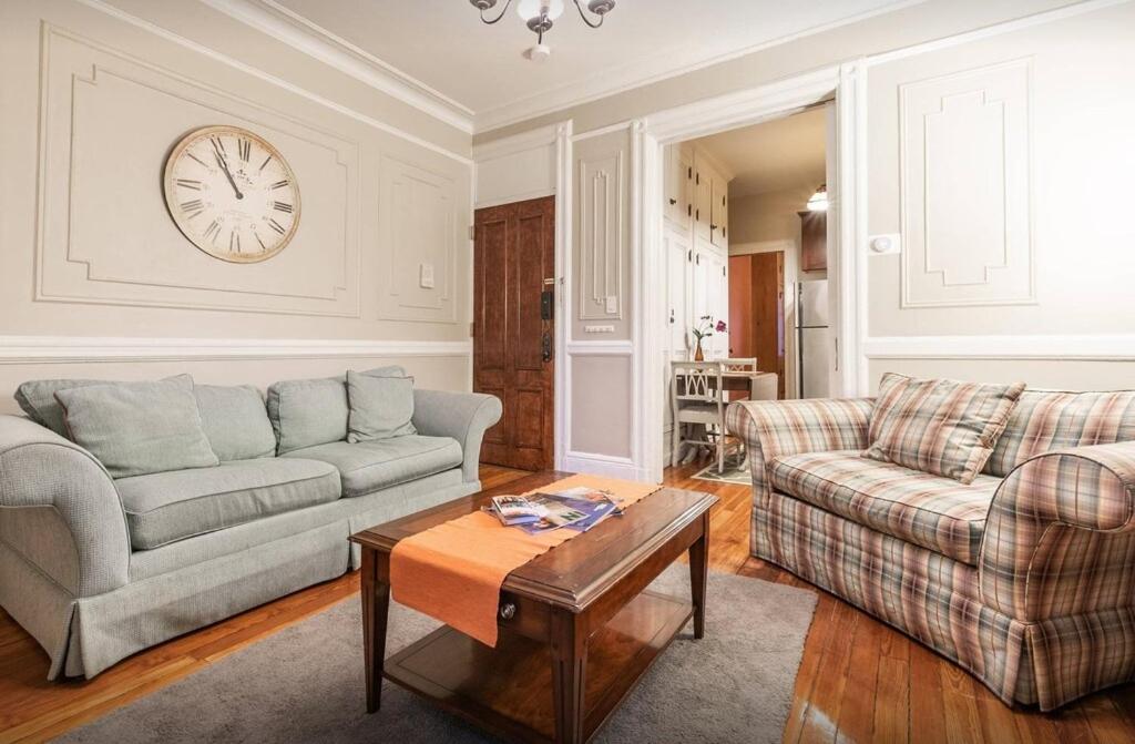 a living room with two couches and a clock on the wall at Amazing 3 Bedroom Apartment in New York