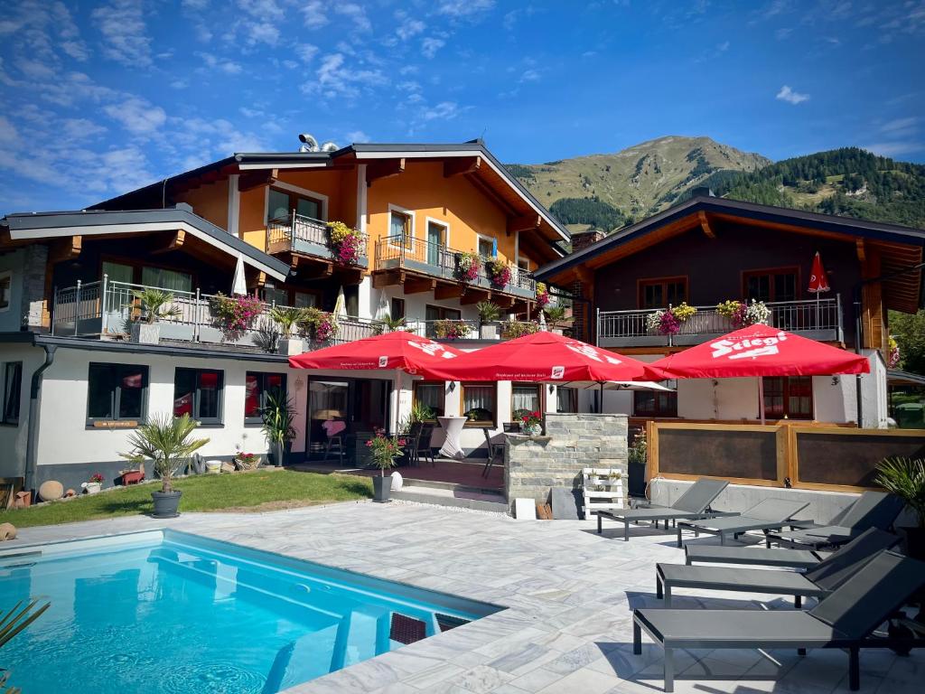 a hotel with a swimming pool with chairs and umbrellas at Hotel-Pension Theresa in Rauris
