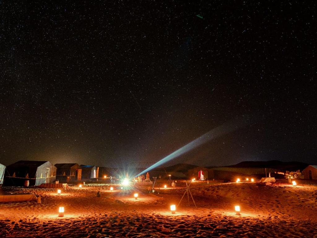 a starry night with lights on a beach at Caravane de Reve in Mhamid