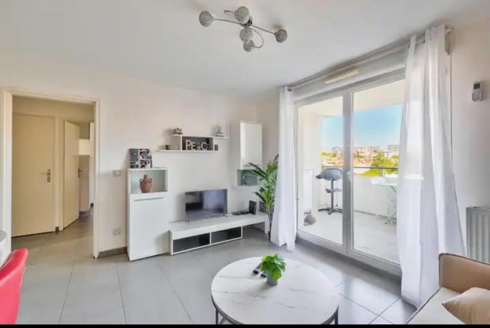 un salon avec une table et une grande fenêtre dans l'établissement MASSALIA FLAT Climatisé, à Marseille