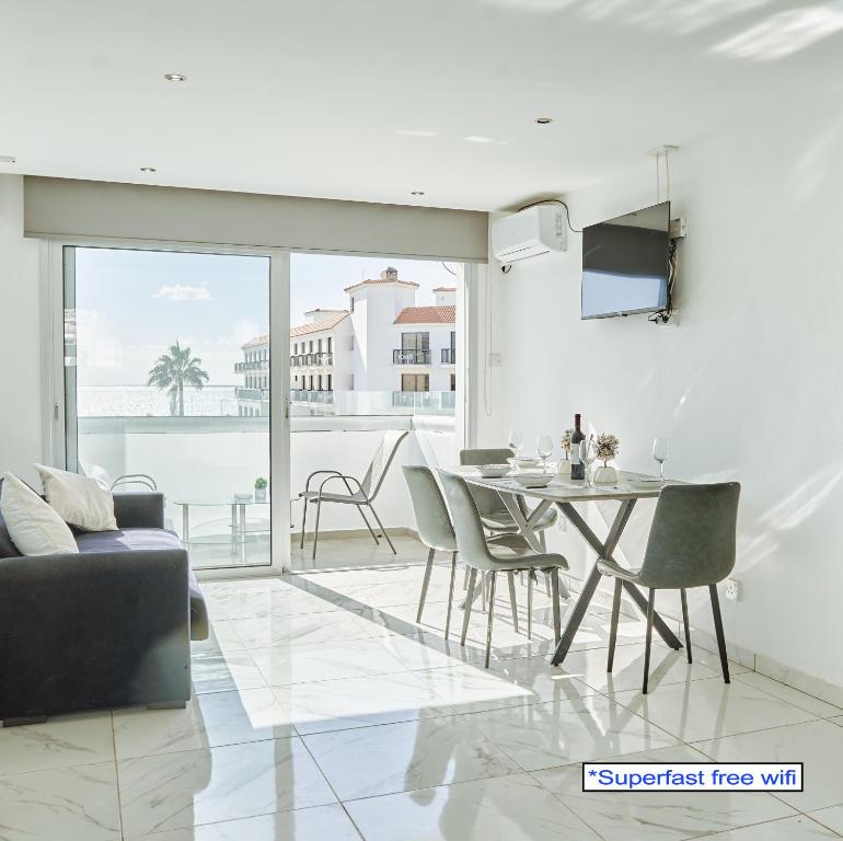 a living room with a table and chairs and a balcony at Nissi Avenue Suites in Ayia Napa