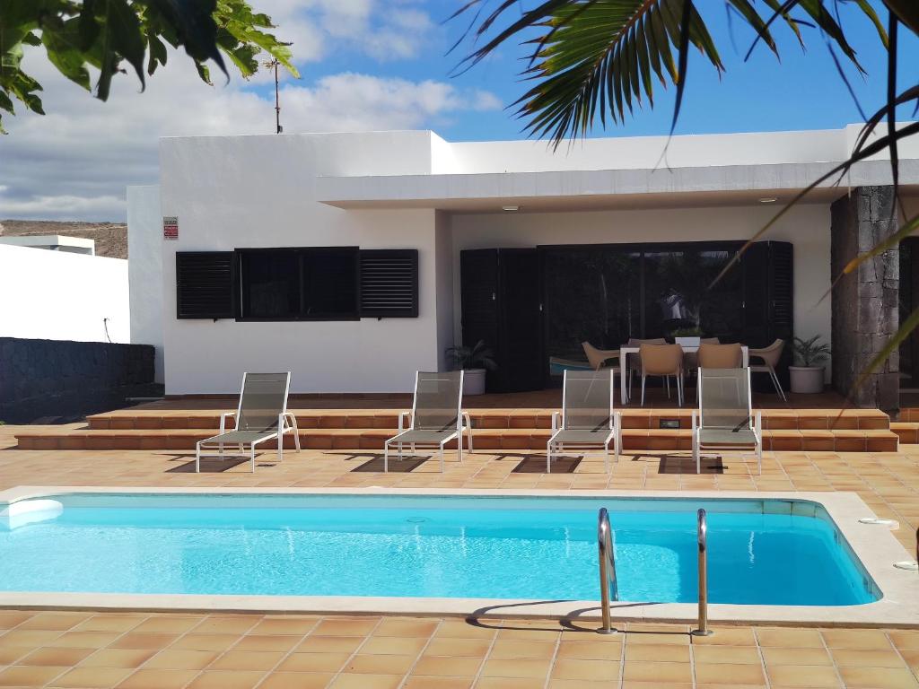 uma piscina com cadeiras e uma casa em Casa Airalba em Tías