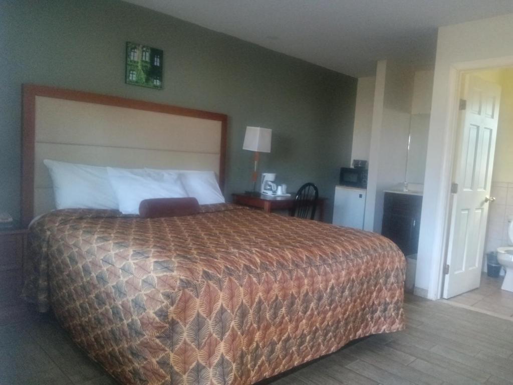 een slaapkamer met een groot bed met een bruine sprei bij Maple leaf motel in New Milford