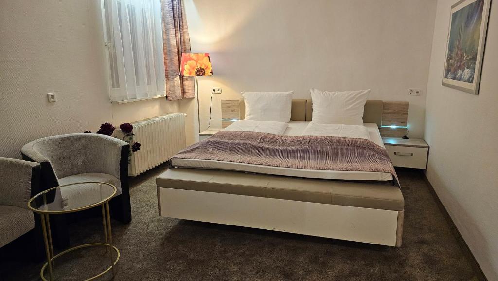 ein Schlafzimmer mit einem großen Bett und einem Stuhl in der Unterkunft Hotel Kölner Hof in Mülheim an der Ruhr
