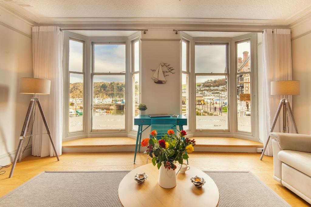 a living room with windows and a table with flowers at Harbour Living in Dartmouth