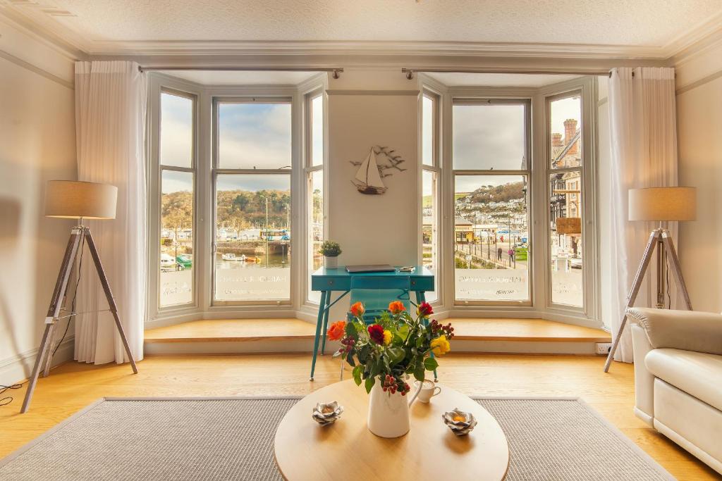 una sala de estar con ventanas y una mesa con flores en Harbour Living, en Dartmouth