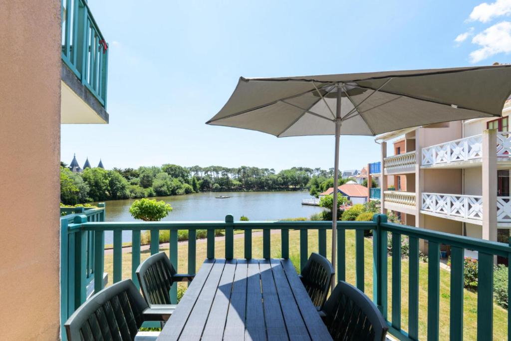 - une table avec un parasol sur un balcon avec une rivière dans l'établissement Résidence Port Bourgenay - maeva Home - Appartement 3 pièces 6 personnes - Prestige MAE-4867, à Talmont-Saint-Hilaire