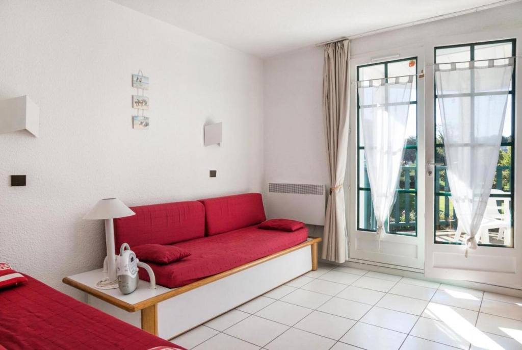 - un canapé rouge dans une chambre blanche avec fenêtre dans l'établissement Résidence Port Bourgenay - maeva Home - 2 Pièces 5 Personnes Confort MAE-5965, à Talmont-Saint-Hilaire