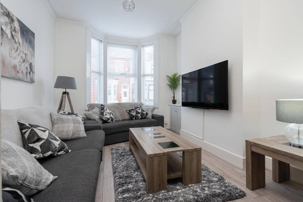 Hornsey Lodge - Anfield Apartments في ليفربول: غرفة معيشة مع أريكة وتلفزيون على الحائط