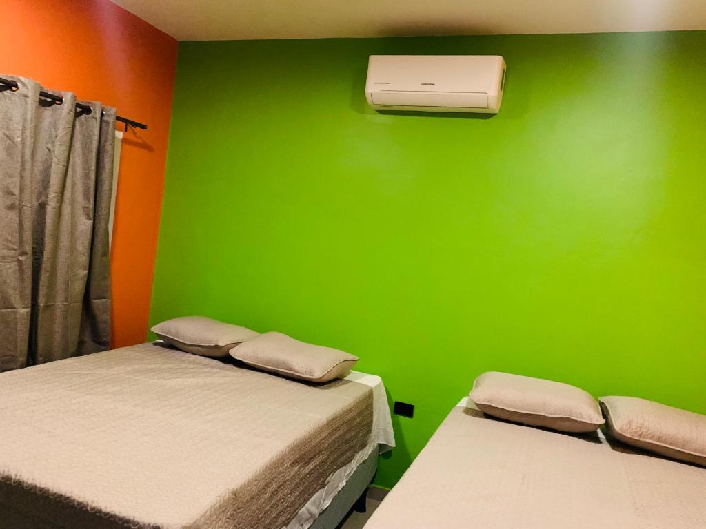 Cette chambre comprend 2 lits et un mur vert. dans l'établissement Cabañas LuMa, à Guanteque