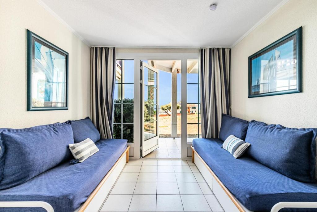 un salon avec des canapés bleus et un balcon dans l'établissement Résidence Port Bourgenay - maeva Home - Appartement 2 pièces 7 personnes - Sélection MAE-2020, à Talmont-Saint-Hilaire