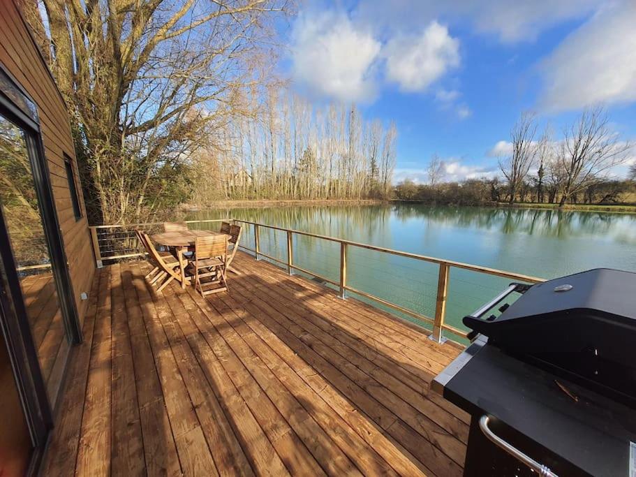 a wooden deck with a table and a grill at Chalet les pieds dans l'eau la campagne à la ville in Saint-Doulchard