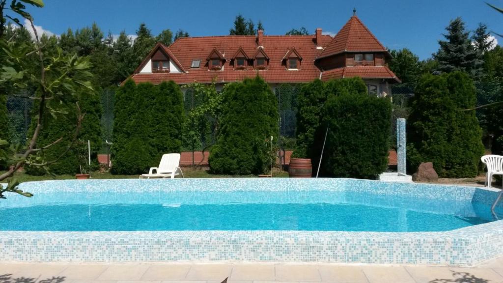 a swimming pool in front of a house at Palatinus Apartmanok in Keszthely