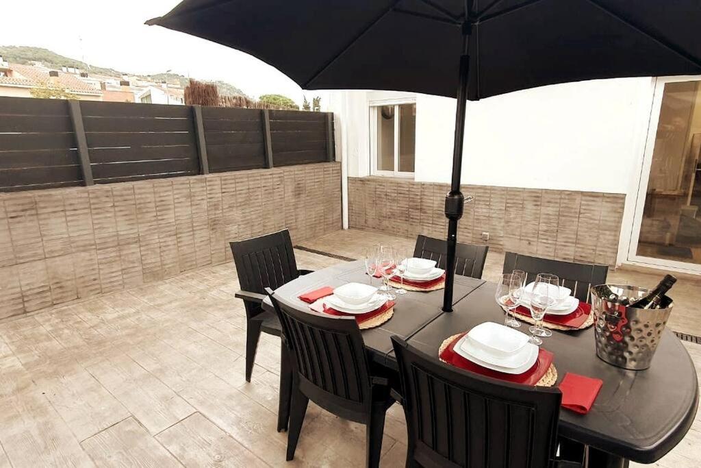una mesa negra con sillas y una sombrilla en el patio en Preciosa casa reformada a 20 min de Barcelona, en Cabrils
