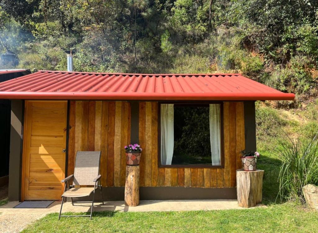 Cabaña pequeña con techo rojo y silla en Rancho Don Efrain, 