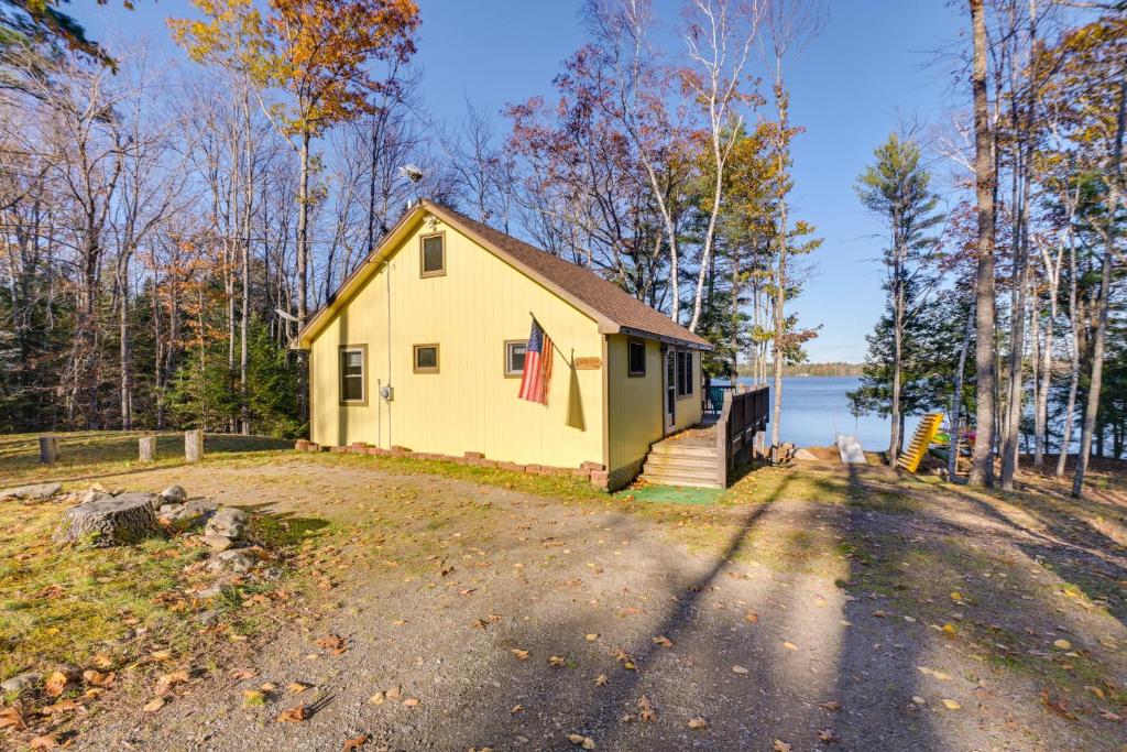 una pequeña casa amarilla al lado de una carretera en Cozy Chemo Pond Cabin with Dock and Waterfront Views, 