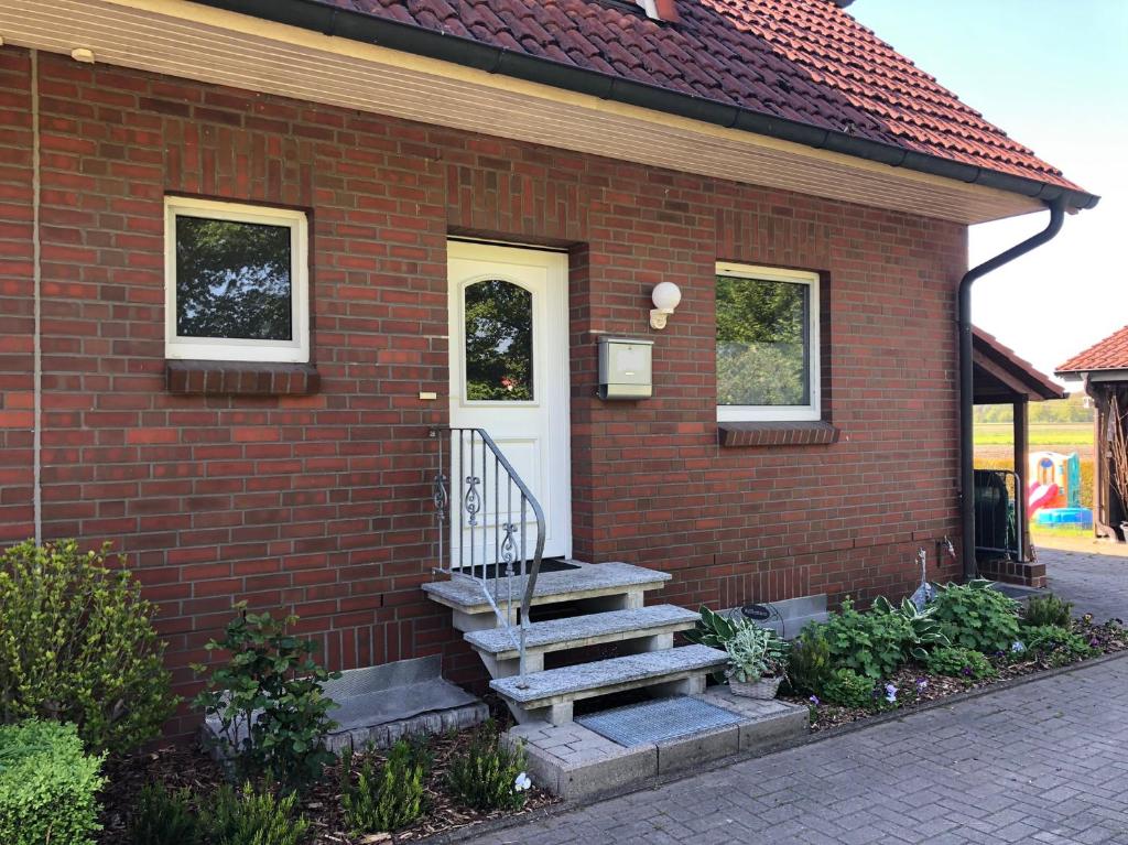 een stenen huis met een witte deur en een trap bij Ferienhaus Ahrensmoor in Ahlerstedt