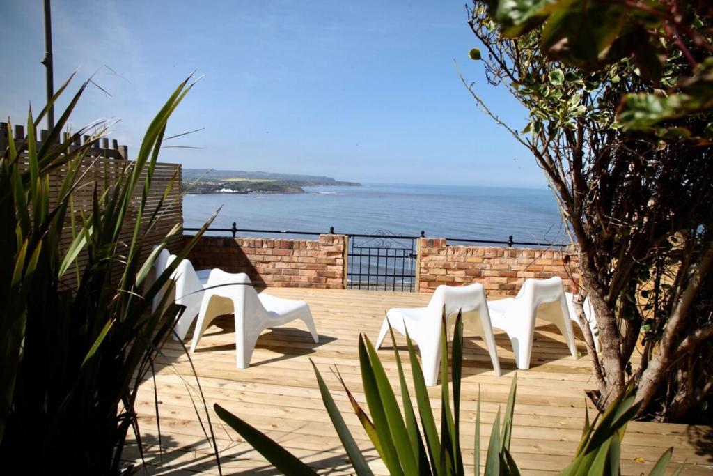 three white chairs sitting on a deck overlooking the ocean at Waimea House Beach Front The best sea views in Scarborough