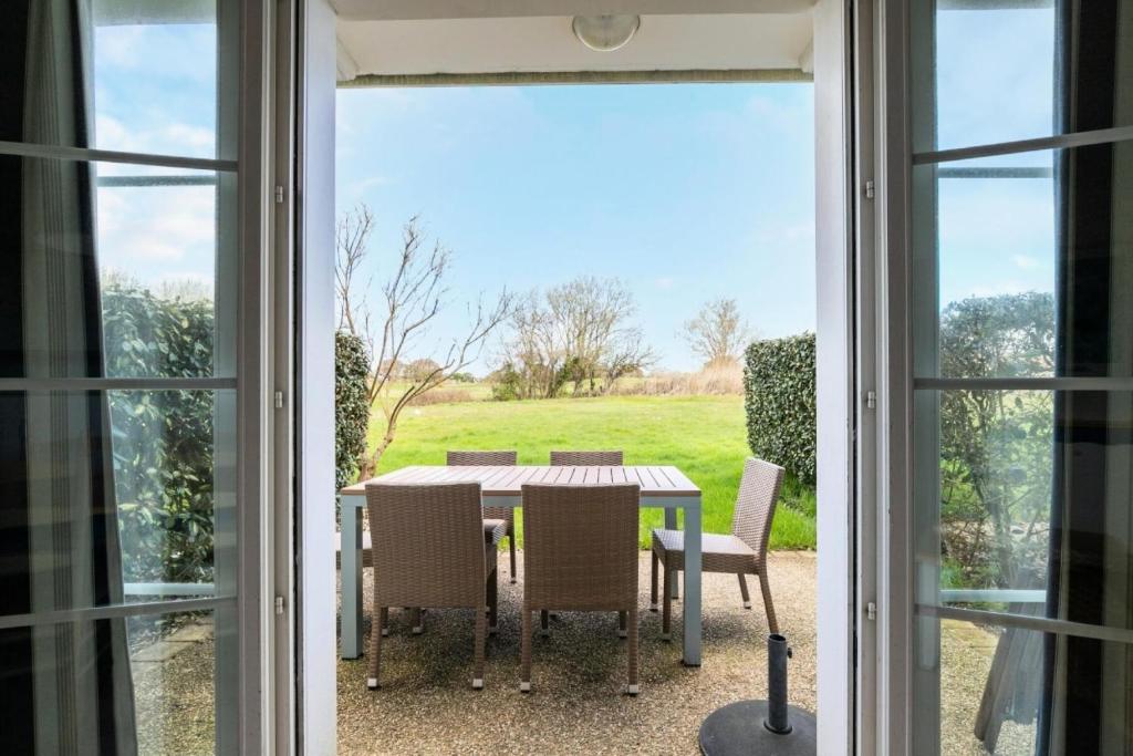 - une table et des chaises sur une terrasse avec vue sur un champ dans l'établissement Les Maisons de Port Bourgenay - maeva Home - Maison 3 pièces 6 personnes - Sélection MAE-6435, à Talmont-Saint-Hilaire
