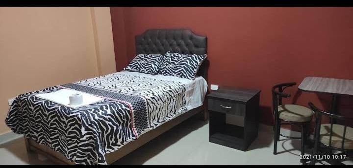 a bedroom with a bed with a black and white comforter at HOSTAL LLAUT * * in Moquegua